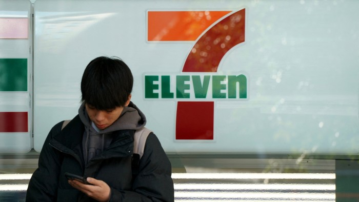 A man stands in front of a 7-Eleven convenience store